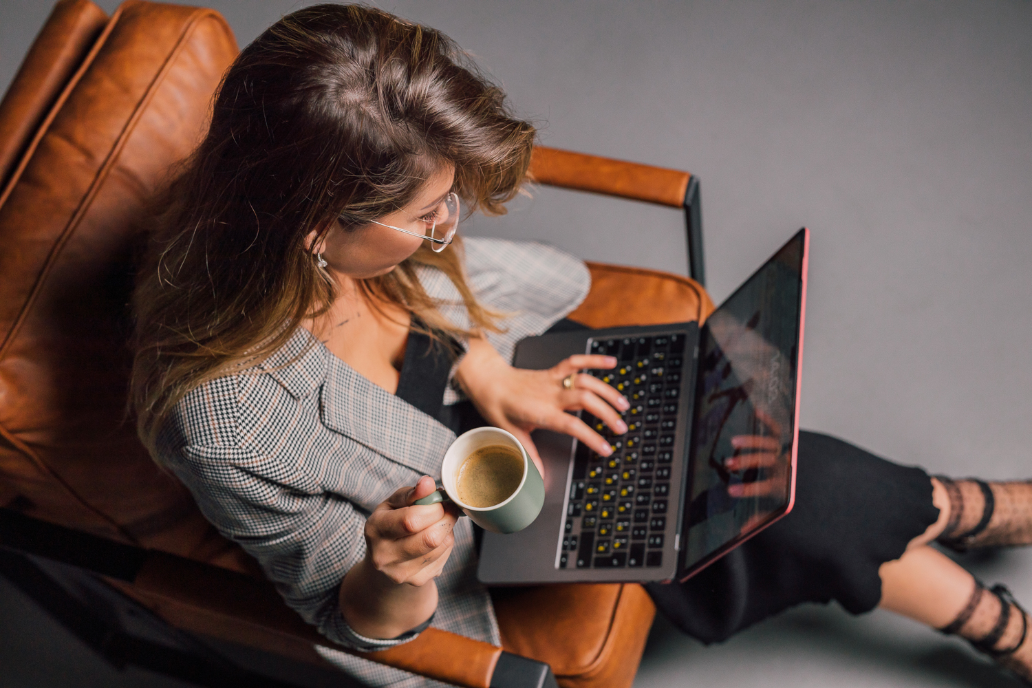 Overhead branding session image with laptop, coffee and warm leather chair