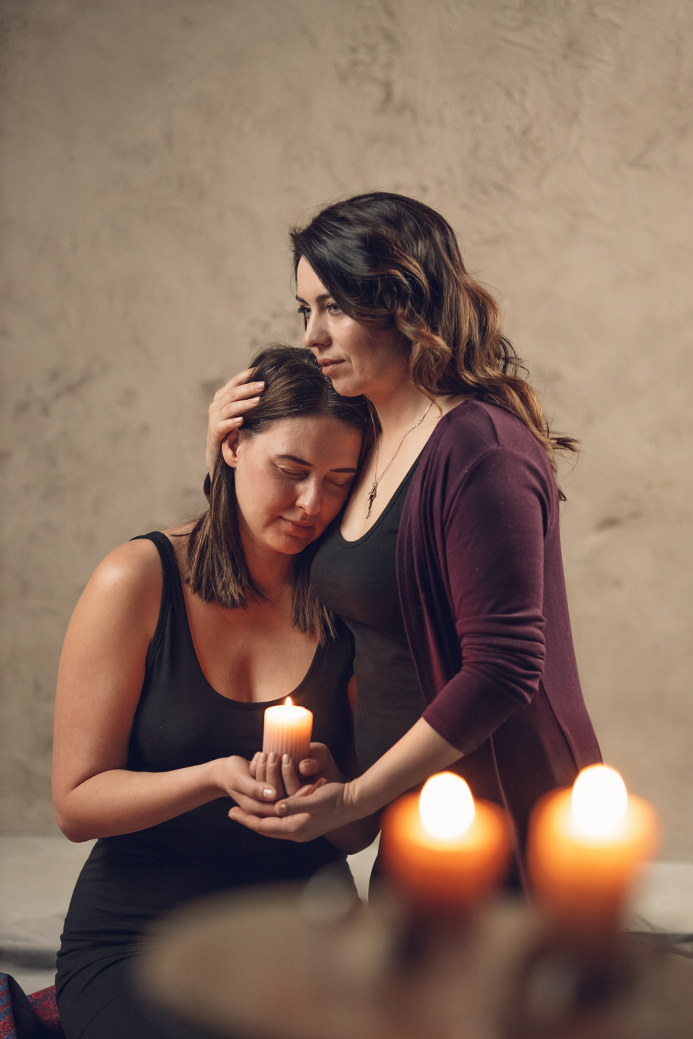 Two women sharing a candle-lit healing moment