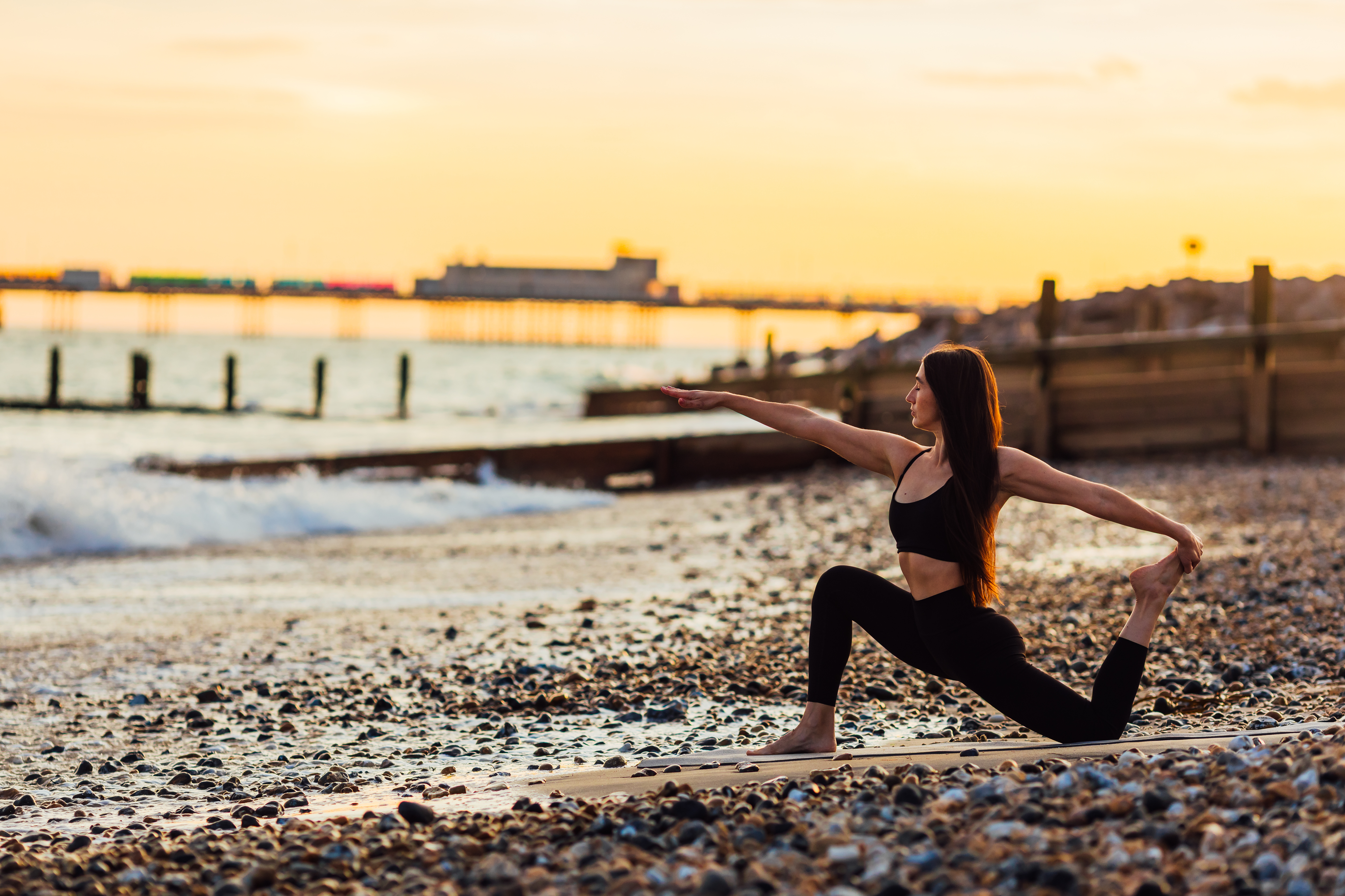 Wide yoga pose on the beach at sunset